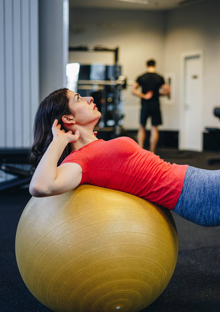 portrait of beautiful fit woman doing abs on a pilates ball. authentic image of slim girl working out in the gym - Photo, Image