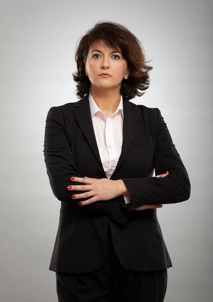 Portrait of a mature businesswoman in suit over gray background - Foto, imagen