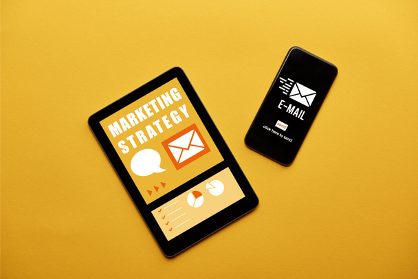 Dijital tablet ve strateji ve e-posta uygulamaları sarı arka plan ekranda pazarlama ile smartphone üstten görünüm - Fotoğraf, Görsel