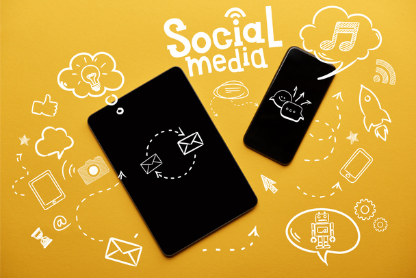 top view of digital tablet and smartphone with social media illustration on yellow background - Photo, Image