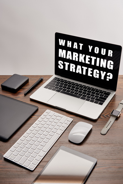 плоский шар гаджетів і ноутбука з питанням вашої маркетингової стратегії на екрані на робочому місці ізольовані на сірому
 - Фото, зображення