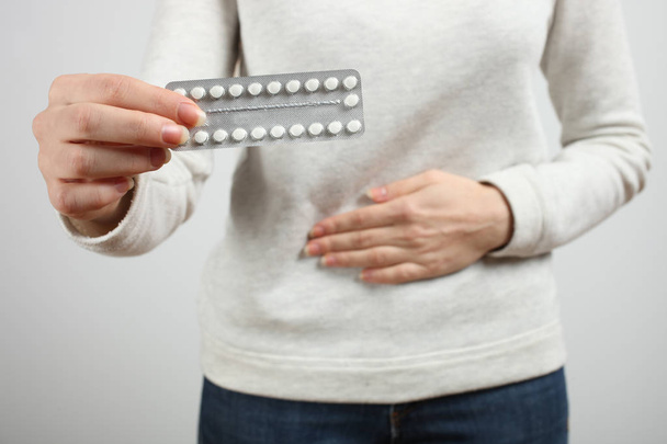 Mujer sosteniendo anticonceptivos orales, píldoras contra el embarazo en un fondo neutro. Concepto ginecología, educación sexual
. - Foto, imagen
