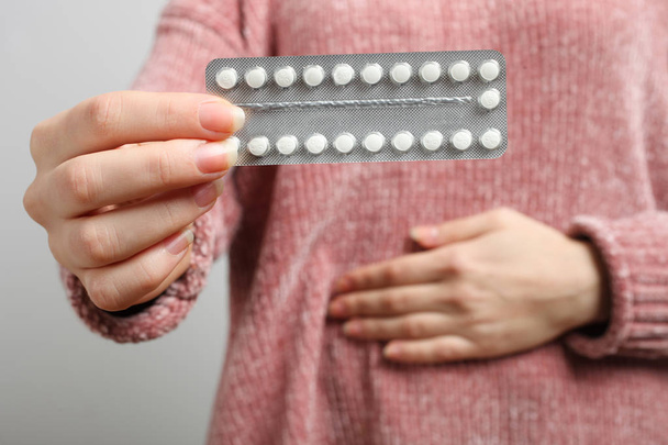 Žena držící orální antikoncepce, pilulky proti otěhotnění na neutrálním pozadí. Koncept gynekologii, sexuální výchova. - Fotografie, Obrázek