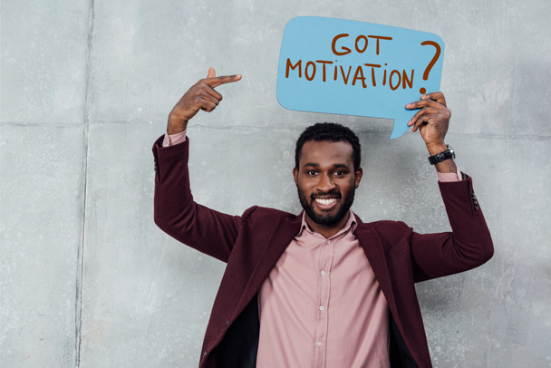 smiling african american casual businessman looking at camera and pointing with finger at speech bubble with got motivation question - Photo, Image