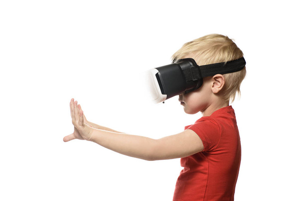 Маленький хлопчик у червоній сорочці відчуває віртуальну реальність, тримаючись за руки перед собою. Ізольовані на білому тлі. Технологія концепції
. - Фото, зображення