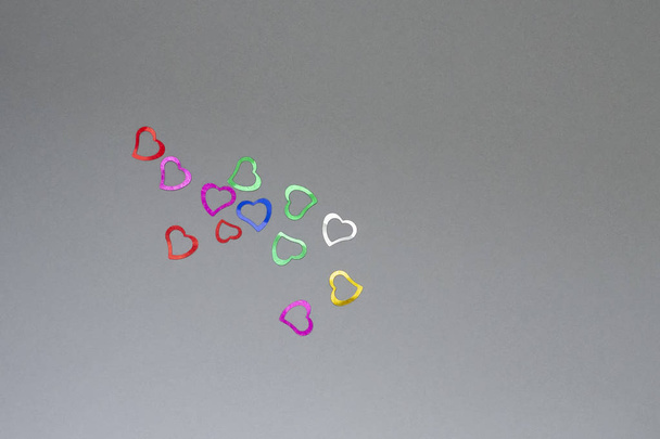 Multicolored shiny hearts on a gray background. Valentine's Day. Place for text. - Photo, image