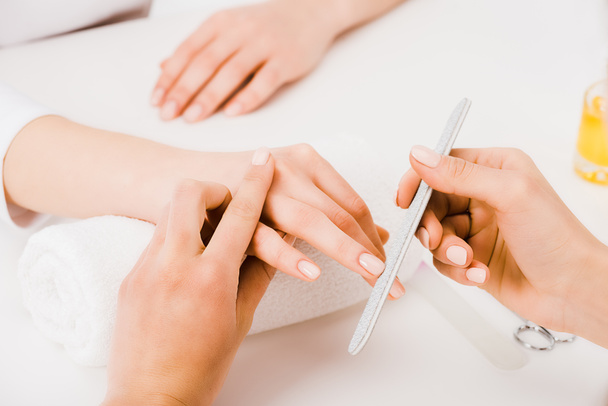 Partial view of manicurist holding fingers while doing nail form - Fotografie, Obrázek