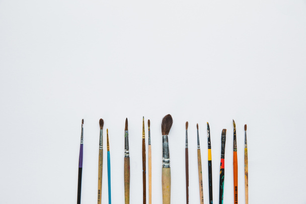 top view of white background with paint brushes placed horizontally - 写真・画像