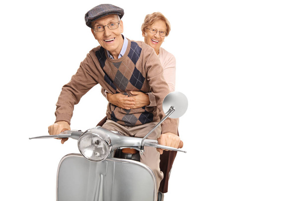 Senior happy couple riding a vintage motorbike isolated on white background - Foto, afbeelding
