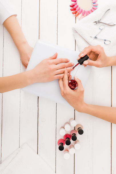 Top view of manicurist applying red nail polish - Φωτογραφία, εικόνα