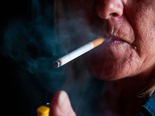Μια ώριμη γυναίκα που καπνίζει ένα τσιγάρο - Φωτογραφία, εικόνα