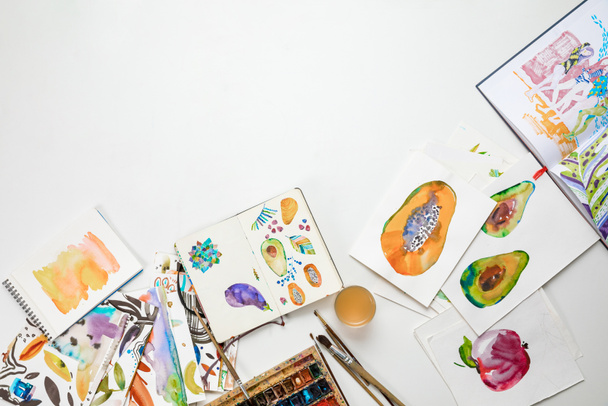 top view of colorful watercolor paintings and drawing utensils - 写真・画像