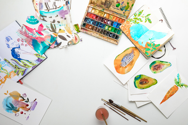 top view of multicolored watercolor paintings and drawing utensils - Photo, Image