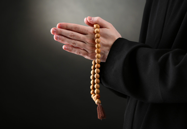 Priest holding rosary, on black background - Foto, Imagem