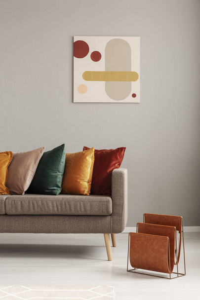 Magazine rack next to beige sofa with pillows in stylish living room interior - Valokuva, kuva