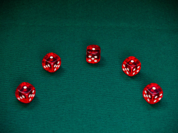 Αρκετές ζάρια κόκκινο με άσπρες κουκκίδες σε ένα καταπράσινο χαλί - Φωτογραφία, εικόνα