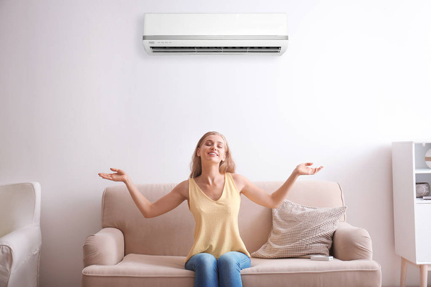 Young woman relaxing near air conditioner at home - Fotoğraf, Görsel
