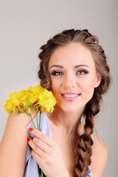 Young woman with beautiful hairstyle and flowers, on grey background - Foto, Imagem