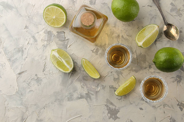 gold tequila in a glass shot glass with salt and lime on a light concrete background. bar. alcoholic beverages. view from above. with space for text - Photo, image