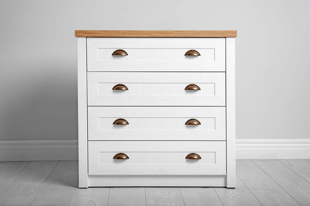 Stylish chest of drawers near white wall. Furniture for wardrobe room - Valokuva, kuva