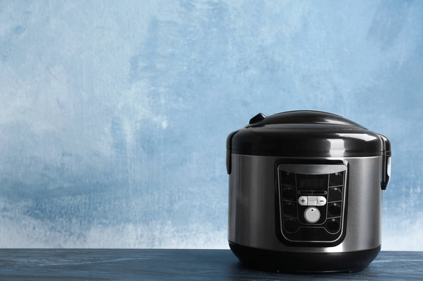 Modern powerful multi cooker on table against color background. Space for text - Zdjęcie, obraz