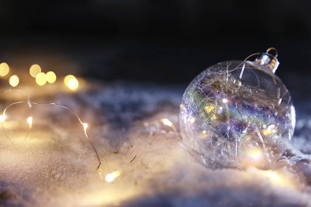 Christmas ball and fairy lights on white snow outdoors. Space for text - Foto, Imagen
