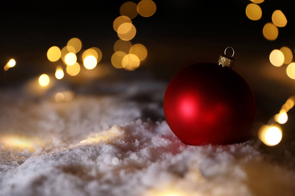 Christmas ball and fairy lights on white snow outdoors. Space for text - Foto, immagini