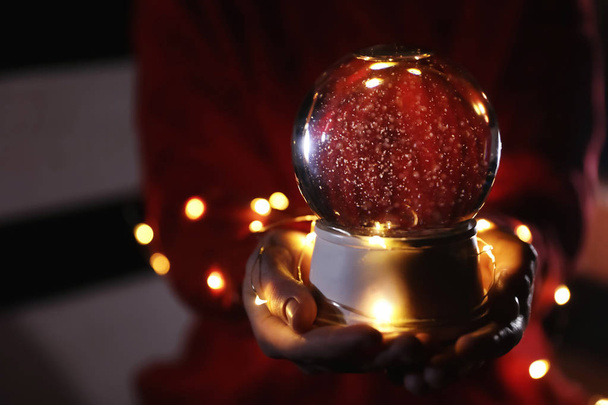 Woman holding snow globe and Christmas lights, closeup. Space for text - 写真・画像
