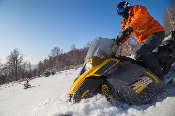Atleta en una moto de nieve que se mueve en el bosque de invierno en las montañas de los Urales del Sur. - Foto, imagen