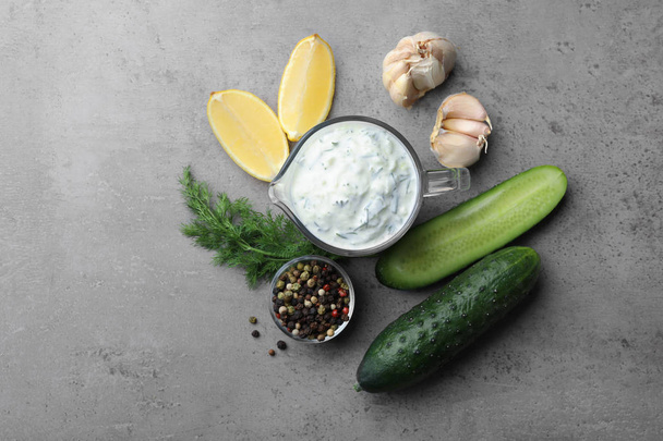 Tzatziki cucumber sauce with ingredients on grey background, flat lay - Foto, Imagem