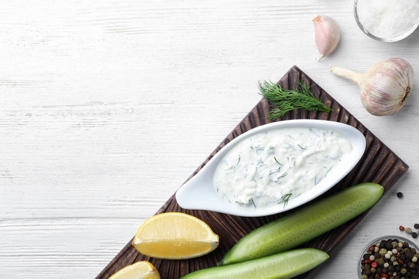 Tzatziki sauce with lemon, cucumber, dill and pepper on white wooden background, top view. Space for text - Фото, зображення
