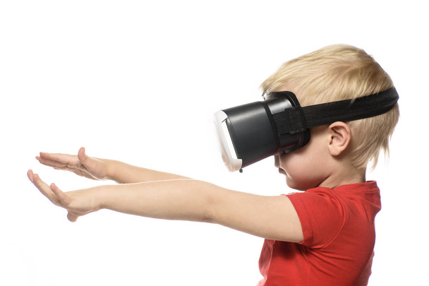 Little boy in a red shirt is experiencing virtual reality holding hands in front of him. Isolate on white background. Technology concept. - Photo, Image