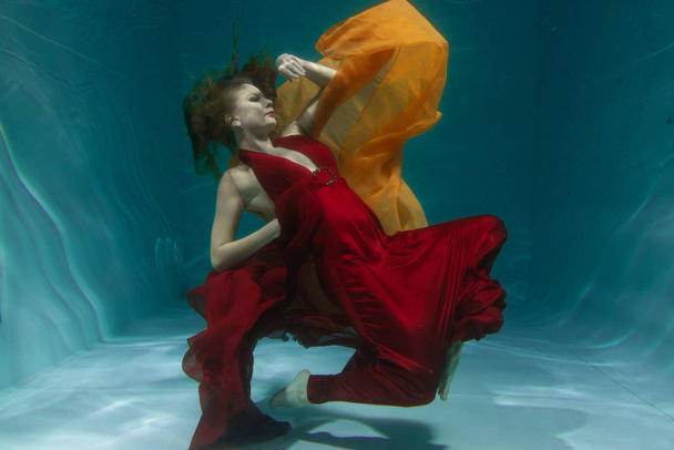 深いだけで水の下の長い赤いイブニング ドレスで泳いでいる美しい無料ダイバー女性 - 写真・画像