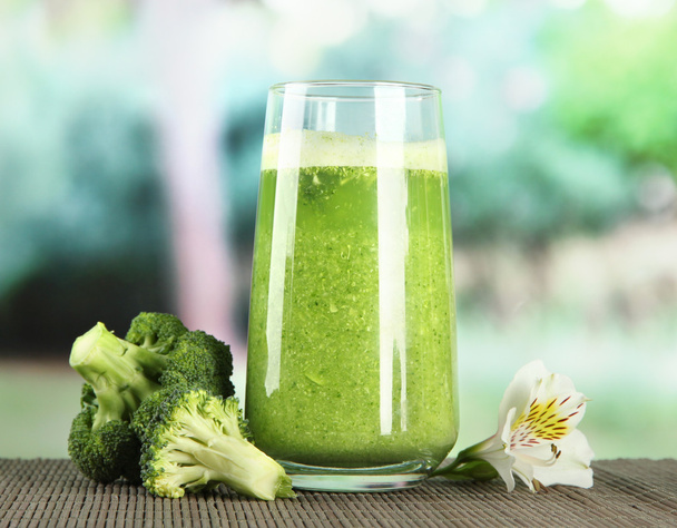 Glass of broccoli juice, on bamboo mat, on green background - Fotó, kép