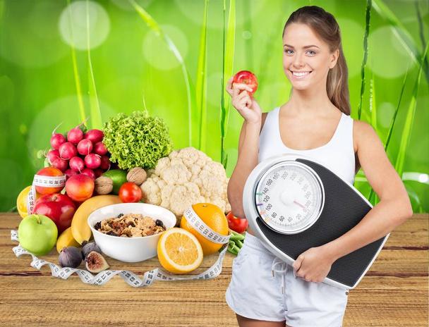 Dieting women holding weight scale, healthy food on background - Φωτογραφία, εικόνα