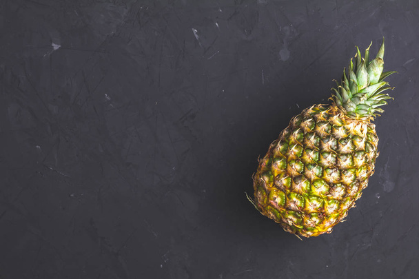 Pineapple on black stone concrete textured surface background. Top view with copy space for your text. - Photo, Image