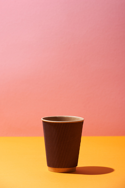 paper coffee cup on yellow surface and pink background - Foto, Bild