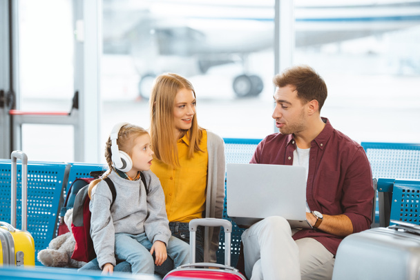 enfant surpris dans les écouteurs regardant papa assis près de la mère à l'aéroport
  - Photo, image
