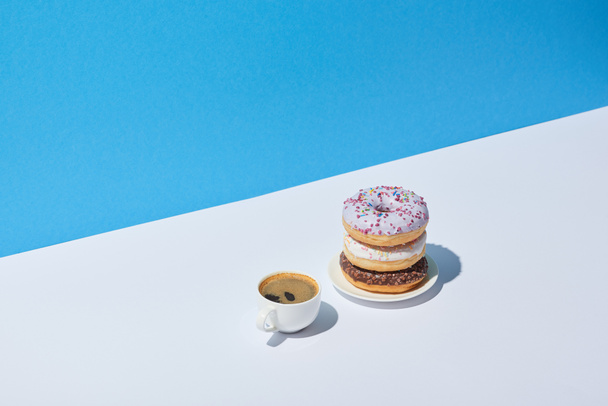 tasty donuts and coffee cup on white desk and blue background - Фото, зображення