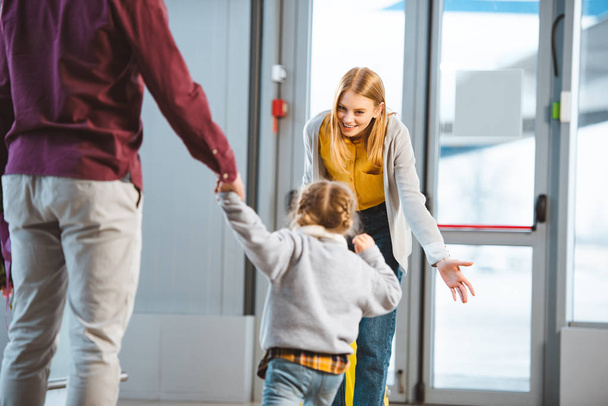 enfoque selectivo de la madre alegre sonriendo a la hija en el aeropuerto
  - Foto, Imagen