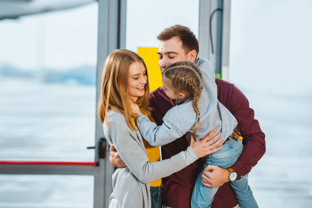 familia alegre sonriendo mientras se abraza en el aeropuerto
  - Foto, Imagen