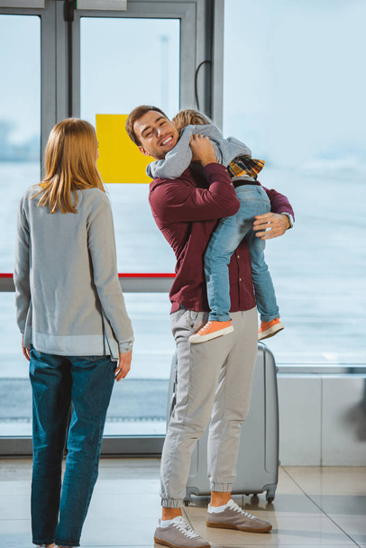 heureux père tenant dans les bras fille près de femme à l'aéroport
  - Photo, image
