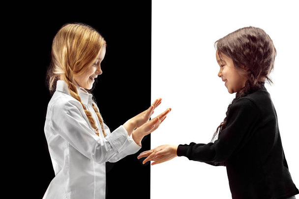 Hand shake and high five. The portrait of two happy holding hands girls on a white and black studio background. Human emotions concept. Comparison. The childhood, smile, happiness, joy, kid, friendship concept - Fotoğraf, Görsel