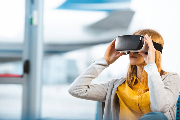 mulher vestindo fone de ouvido realidade virtual enquanto está sentado na sala de partida
 - Foto, Imagem