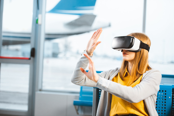 mulher vestindo fone de ouvido realidade virtual enquanto sentado no aeroporto
 - Foto, Imagem