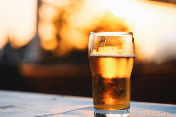 Δροσιστικό κρύο ποτήρι της μπύρας σε πίνακα στο ηλιοβασίλεμα - Φωτογραφία, εικόνα