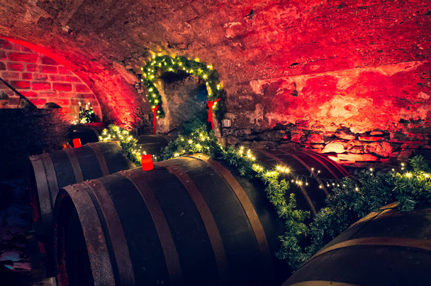Barris de vinho em uma antiga adega com velas vermelhas e luzes de fadas
 - Foto, Imagem
