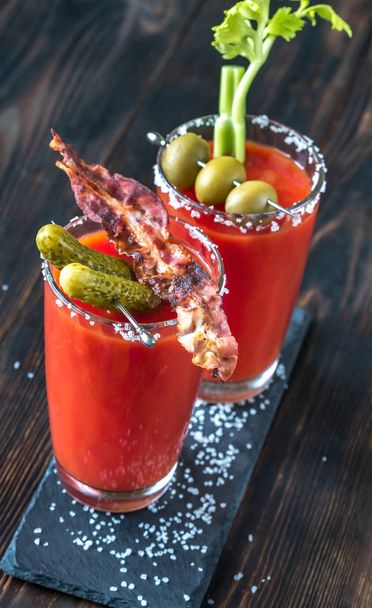 Two glasses of Bloody Mary garnished with gherkins and celery stalk - Foto, Imagen
