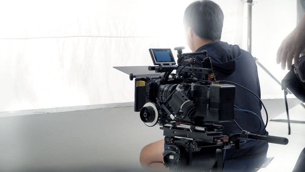 Za kamerą wideo, która nagrywa online film reklamowy lub filmowy w dużym studio produkcyjnym z profesjonalnym sprzętem, takim jak kamera i monitory wysokiej rozdzielczości oraz oświetlenie LED z zespołem ekipy - Zdjęcie, obraz