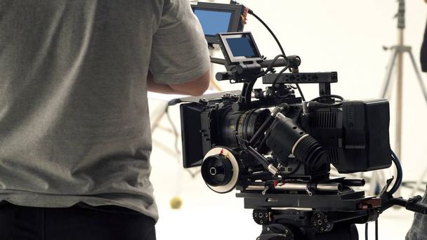 Behind video camera that recording online commercial or web film movie in the big studio production with professional equipment such as high resolution cam and monitors and LED light with crew team set - Photo, Image